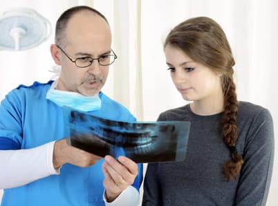 Zahnarzt, Kieferorthopäde oder Zahnchirurg bespricht Röntgenbild mit Patient