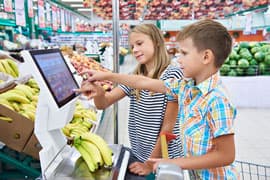 Kinder an einer elektronischen Kundenwaage in Obst- und Gemüseabteilung eines Lebensmittelmarktes