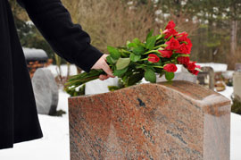 Rosen werden am Grabstein nach einem Sterbefall niedergelegt
